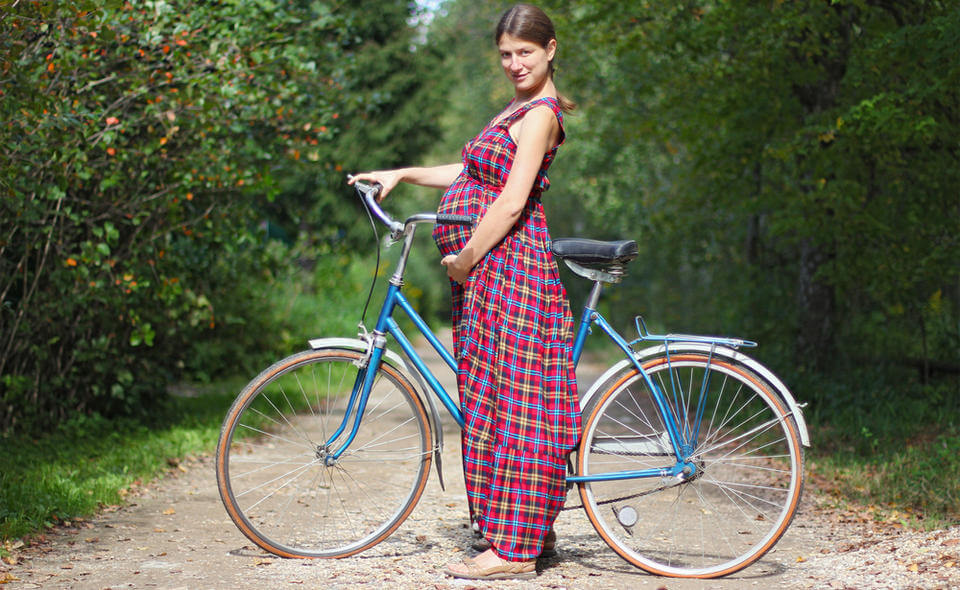 Беременная девушка рядом с велосипедом