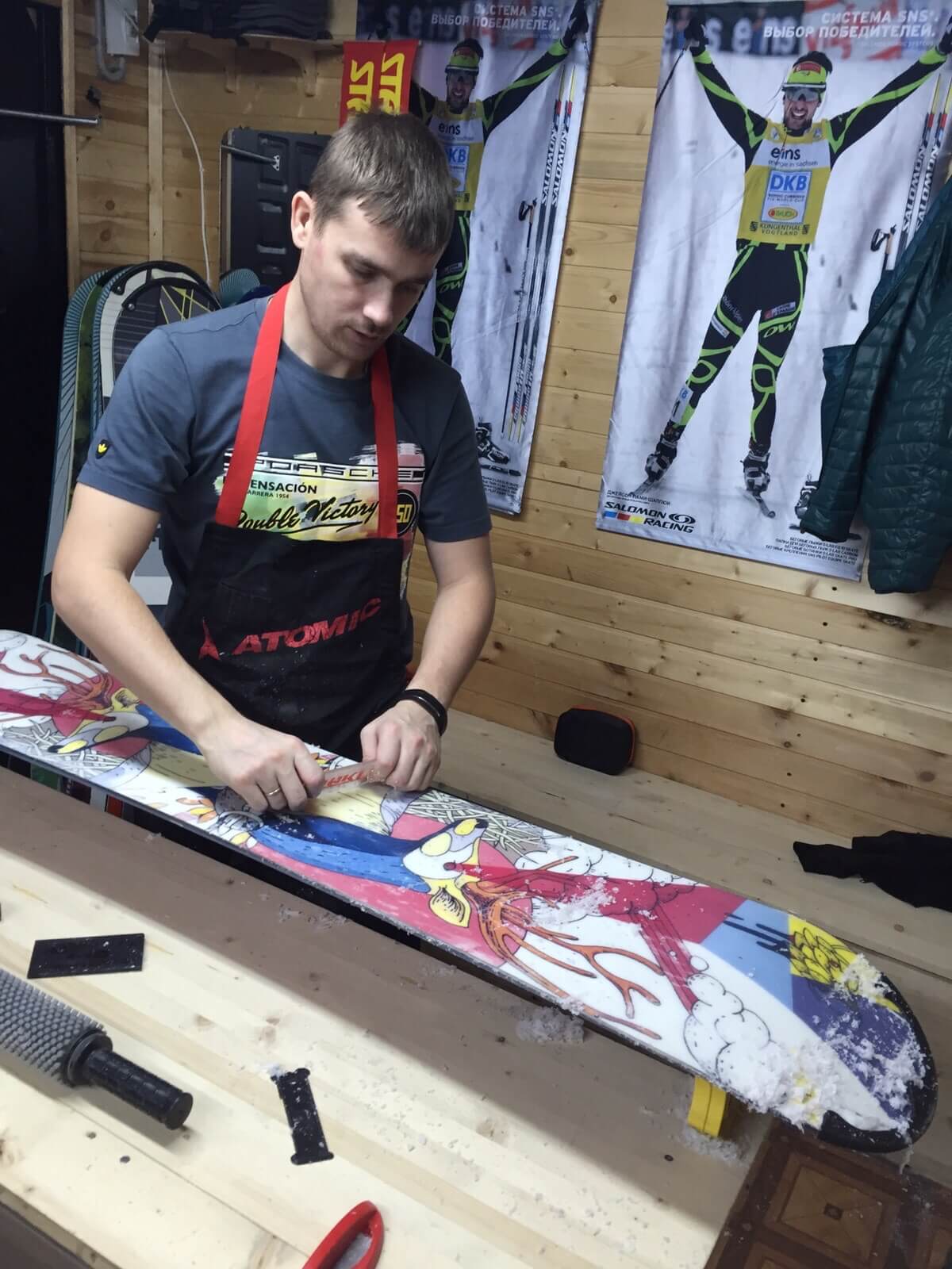 Антон Крутиков обрабатывает парафином сноуборд в прокате на Академической